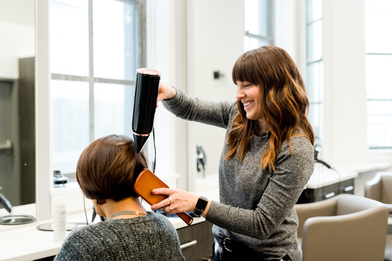 A stylist blow-drying a client in a bright salon